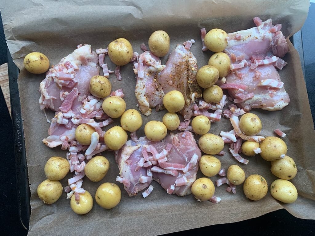 De bakplaat beleggen met de kip, aardappelen en spekjes