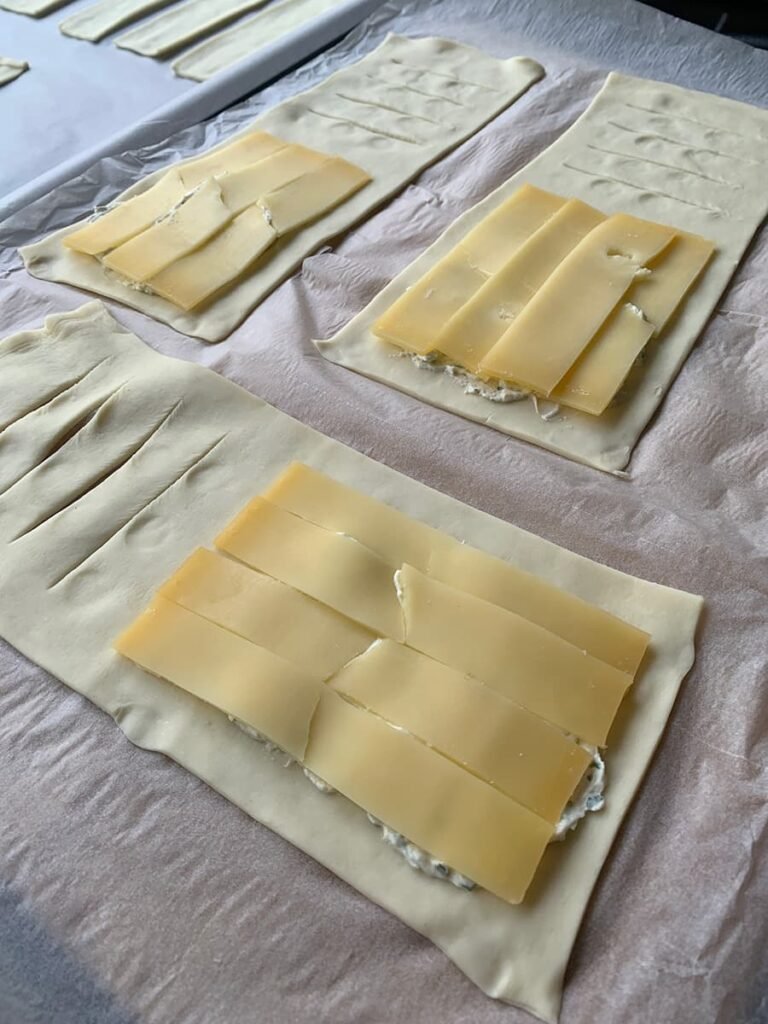 Bladerdeeg kaasbroodjes met roomkaas en oude kaas beleggen