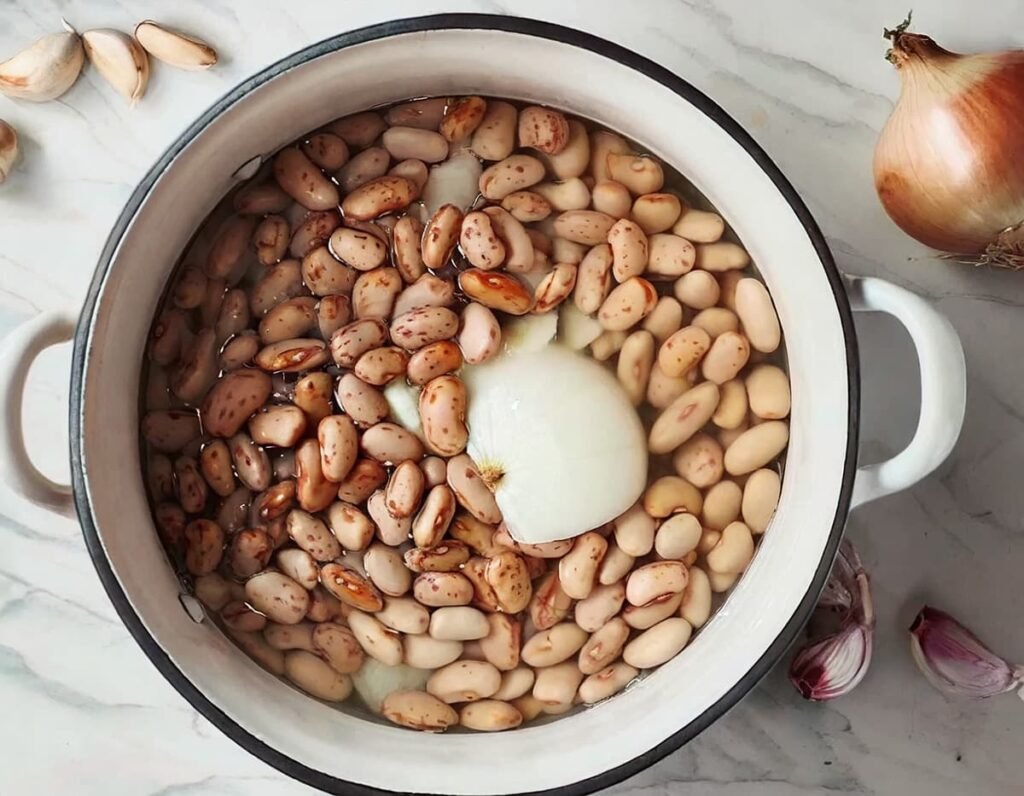 2. Bonen in een grote pan met water, ¼ ui en 1 teentje knoflook