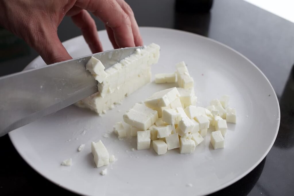 Hak de feta in blokjes voor in de Griekse pastasalade.